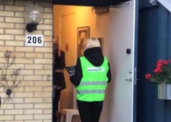 En person med Furuboda-väst står i en dörröppning till en villa och talar med en person om möjligheten att stödja kursverksamheten